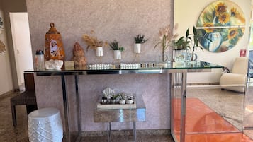 Un mostrador de recepción con cubierta de vidrio, rodeado de objetos decorativos y plantas.