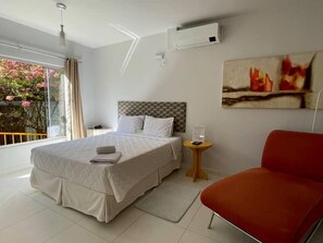 Habitación de hotel con una cama grande, una silla roja, una mesita y un cuadro en la pared.