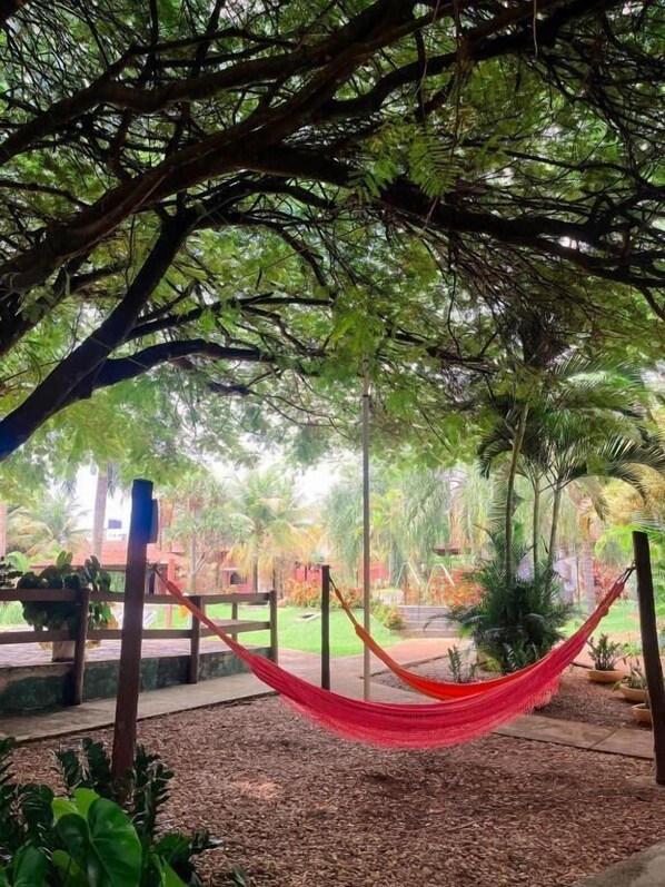 A hammock under a tree canopy in a garden setting. - Rosa Spa e Pousada (Aparecida de Goiânia)
