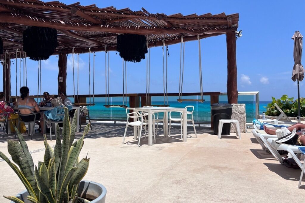 An outdoor seating area with tables and chairs, overlooking a body of water.