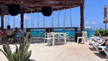 An outdoor seating area with tables and chairs, overlooking a body of water.