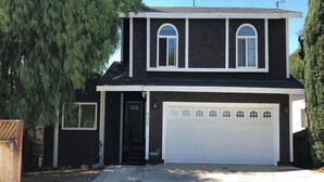 Une maison à deux étages avec un garage, une porte d’entrée et un petit porche.