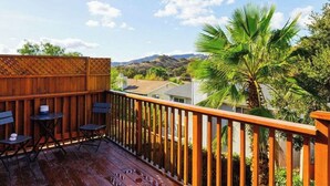 Une terrasse en bois avec une rambarde, deux tables et une chaise.