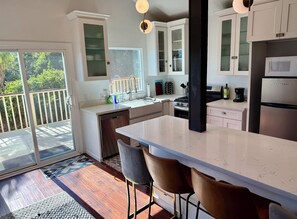 Una cocina moderna con una isla grande, taburetes de bar y una puerta corrediza de vidrio que da a una terraza.