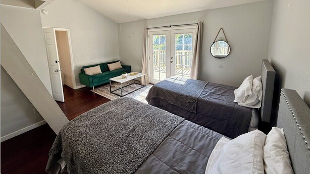 Une chambre avec deux lits, un ventilateur de plafond, une fenêtre avec des rideaux et une petite table.