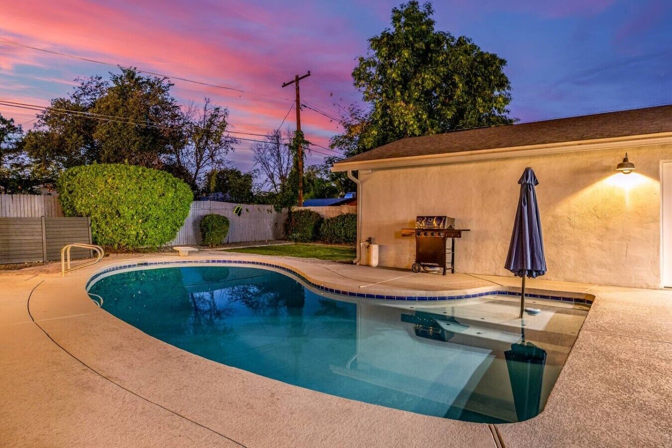 Una piscina con hidromasaje, una parrilla de barbacoa y un patio cubierto.