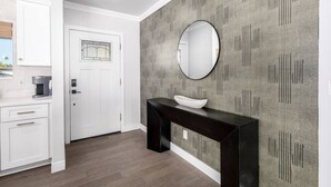 Une cuisine moderne avec des meubles blancs, une console noire et un mur gris à motifs.