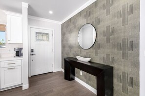 A modern kitchen with white cabinetry, a black console table, and a grey patterned wall. - Pickleball Ball Paradise (Phoenix)