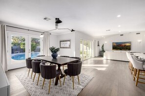 Un espace repas moderne avec vue sur la piscine, un grand tableau et un design minimaliste.