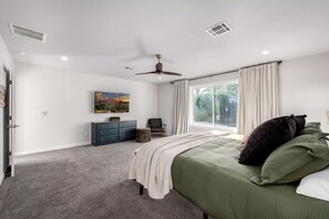 A bedroom with a bed, a dresser, a chair, a window, and a ceiling fan. - Pickleball Ball Paradise (Phoenix)