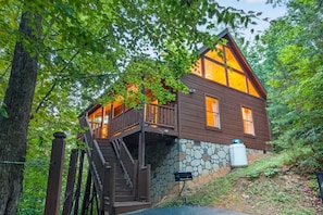 A cabin with a stone foundation, wooden exterior, and a balcony with a staircase. - Moonshine Romance Wood Cabin Retreat (Sevierville)