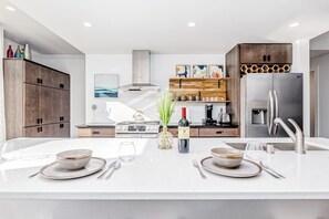 Una cocina moderna con una isla central, electrodomésticos de acero inoxidable y armarios de madera.