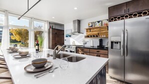 Una cocina moderna con una isla grande, electrodomésticos de acero inoxidable y vistas al exterior.
