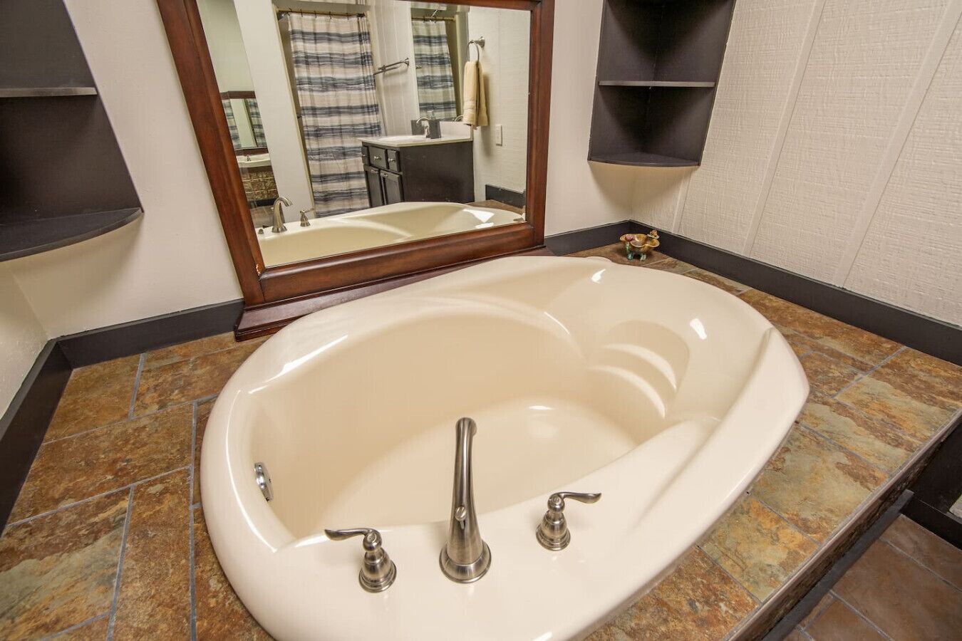 A bathroom with a freestanding bathtub, a mirror, and a tiled floor.