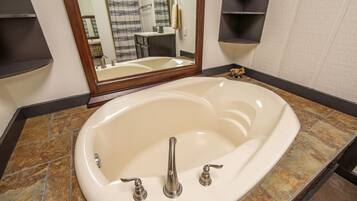 A bathroom with a freestanding bathtub, a mirror, and a tiled floor.