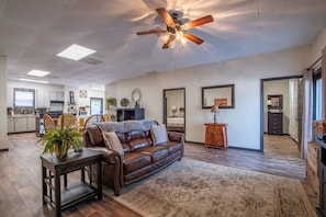 A spacious living area with a leather sofa, a coffee table, and a ceiling fan.