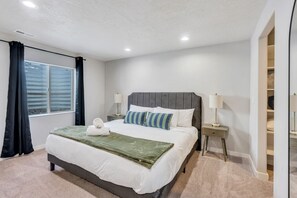 Een hotelkamer met een groot bed, twee nachtkastjes, een raam met gordijnen en een kledingkast met spiegel.