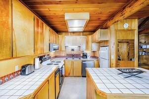 A compact kitchen with wooden cabinets, a microwave, a stove, and a refrigerator.