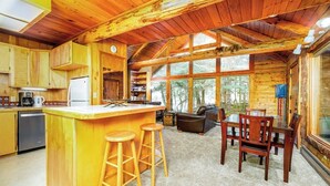 L’intérieur d’une cabane comprend une cuisine, un coin repas et de grandes fenêtres.