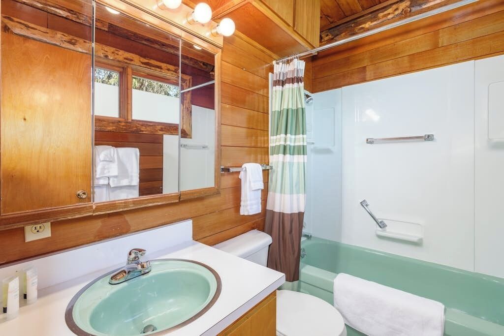 Un bagno con finiture in legno, un lavandino, un water e uno spazio doccia.