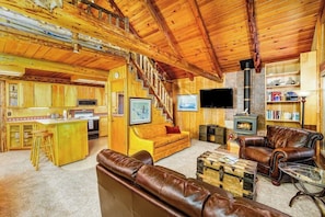 A log cabin interior with a kitchen, living area, and fireplace. - Classic Log Cabin w/ Expansive Deck Near Alyeska Base (Girdwood)