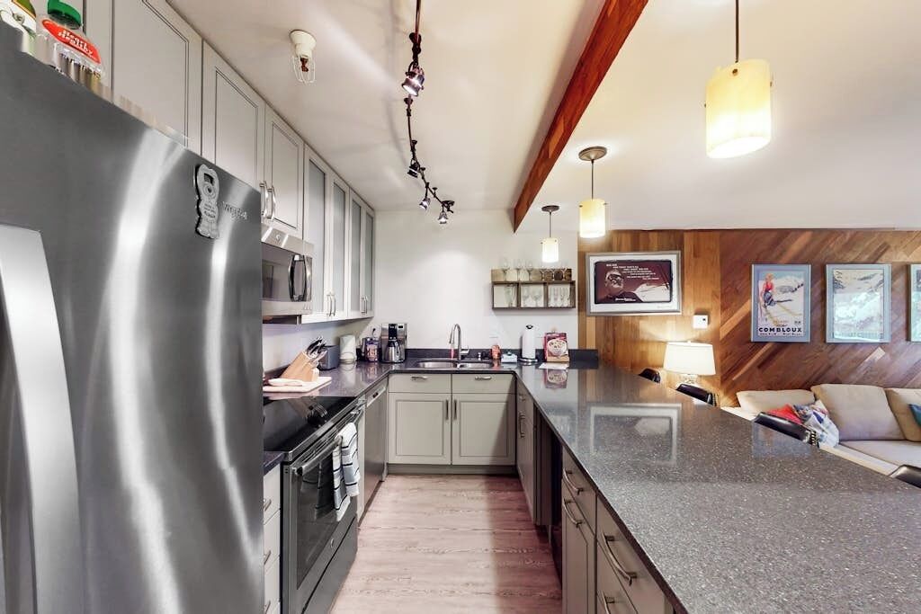 Una cocina moderna con electrodomésticos de acero inoxidable, encimera de granito y detalles de madera.