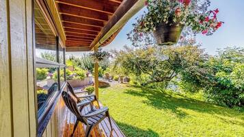 A wooden deck with outdoor furniture, a hanging flower basket, and a well-maintained garden.