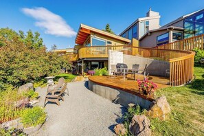 A modern house with a deck, outdoor seating, and a landscaped garden.