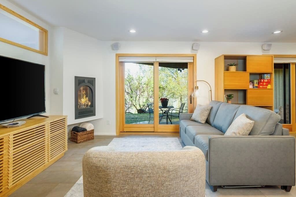 A modern living room with a television, a fireplace, a sofa, and a bookshelf.