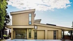 A modern two-story house with a garage, large windows, and a covered patio area. - Full Downtown Anchorage Triplex for Large Groups (Anchorage)