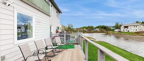 A waterfront property with a deck, rocking chairs, and a view of the river.