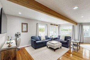 A modern living room with a wooden ceiling, two sofas, a coffee table, and a fan. - Elegant Anchorage Lakehouse w/ Direct Water Access (Anchorage)