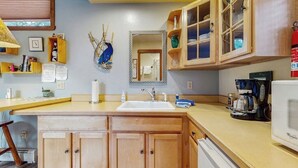 A kitchen with wooden cabinets, a sink, a coffee maker, and a microwave. - Glacier-view Studio w/ Its Own Private Entrance (Girdwood)
