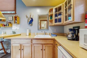 Una cocina con armarios de madera, un lavamanos, una cafetera y un microondas.