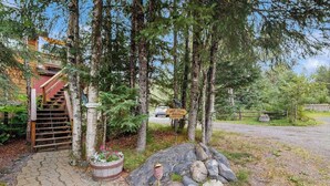 A wooden staircase leading to a building, surrounded by trees and a gravel path. - Glacier-view Studio w/ Its Own Private Entrance (Girdwood)