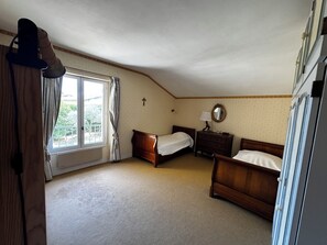 A bedroom with two wooden beds, a dresser, a mirror, and a window with curtains. - Family villa with a pool and garden, featuring a view (Caumont-sur-Durance)