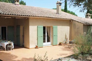 A building with a tiled roof, a covered patio area with tables and chairs, and a small garden. - Family villa with a pool and garden, featuring a view (Caumont-sur-Durance)