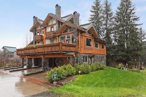 A large, multi-story log cabin with a stone foundation, a wooden deck, and a private entry sign.