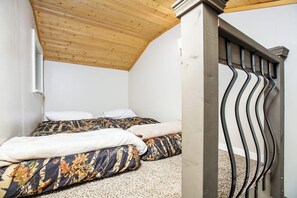 Ein Schlafzimmer mit zwei Betten, einer Holzbalkendecke und einem Metallgeländer.