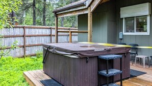 Un jacuzzi en una terraza de madera, con una valla de madera al fondo.