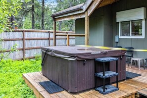 Ein Whirlpool auf einer Holzterrasse mit einem Holzzaun im Hintergrund.