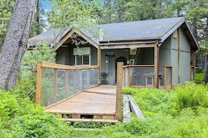 Eine Holzhütte mit einer Holzterrasse, umgeben von dichtem Grün.