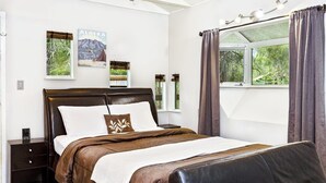 Un dormitorio con cama, mesitas de noche, una ventana con cortinas y decoración en la pared.