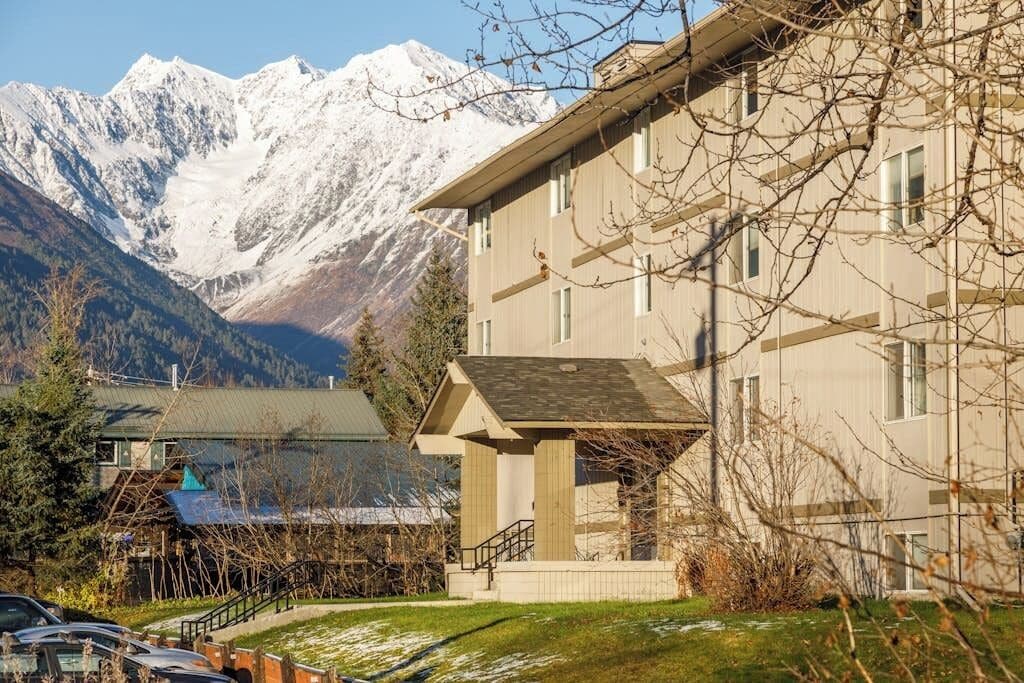 A hotel with a mountain view, a covered outdoor area, and a parking lot.