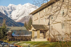 Un hotel con vista a la montaña, un espacio exterior cubierto y aparcamiento.