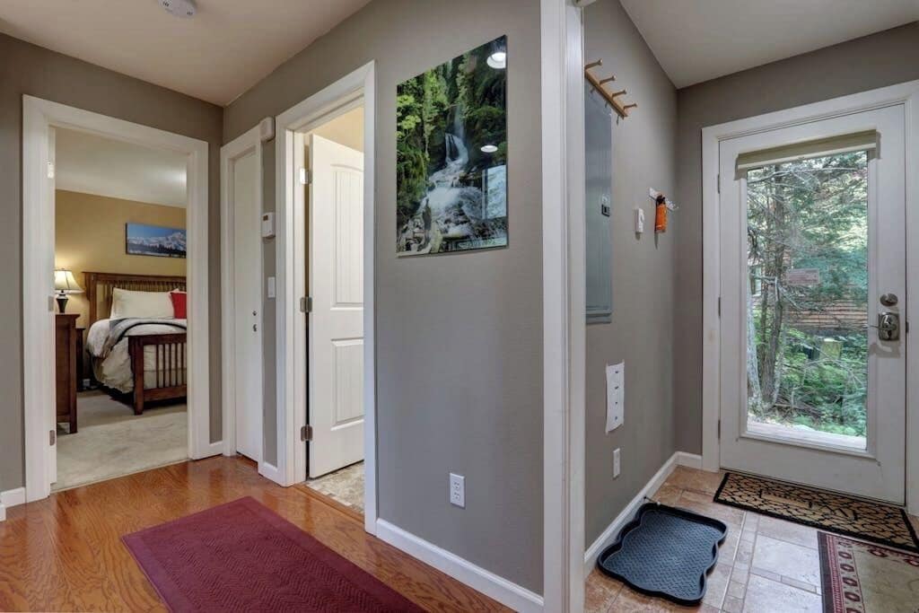 Ein Flur mit Holzboden, einem roten Teppich, einer Tür mit Fensterglas und einem gerahmten Bild an der Wand.