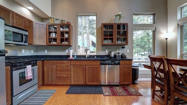 A modern kitchen with wooden cabinets, stainless steel appliances, and a large window providing natural light. - Girdwood Lodge w/ Sauna, Near Alyeska Resort (Girdwood)