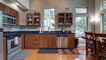 A modern kitchen with wooden cabinets, stainless steel appliances, and a large window providing natural light.