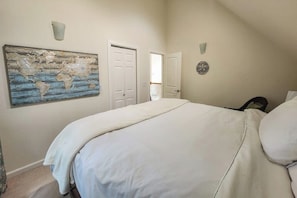 A bedroom with a large bed, a world map artwork, a door, and a wall clock. - Girdwood Lodge w/ Sauna, Near Alyeska Resort (Girdwood)