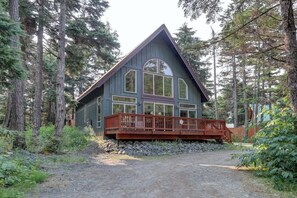A cabin with a wooden deck, surrounded by tall trees. - Girdwood Lodge w/ Sauna, Near Alyeska Resort (Girdwood)